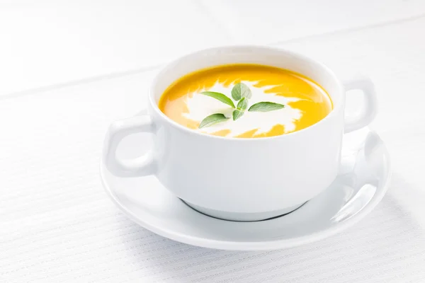 Pumpkin soup with basil on served table — Stock Photo, Image