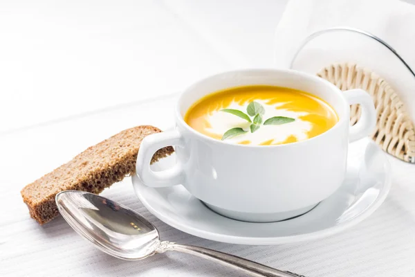 Pumpkin soup with basil on served table — Stock Photo, Image