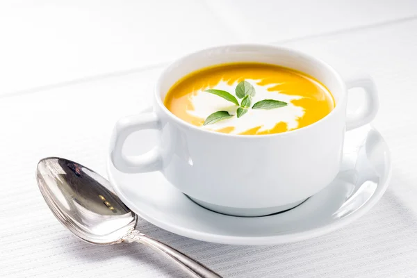 Pumpkin soup with basil on served table — Stock Photo, Image