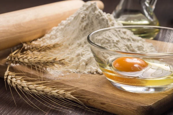 Baking ingredients with wheat ears on wood board — Stock Photo, Image