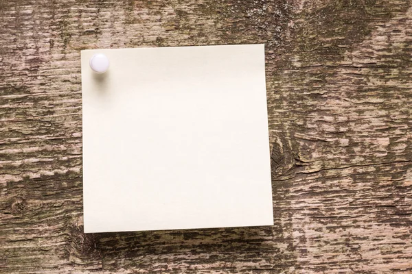 Etiqueta engomada de papel amarillo sobre fondo envejecido de madera — Foto de Stock