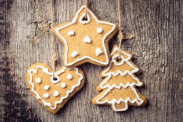 Biscoitos de gengibre pendurados sobre fundo de madeira. Decoração de Natal — Fotografia de Stock