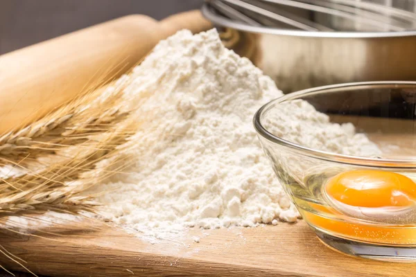 Baking ingredients with wheat ears on wood board — Stock Photo, Image