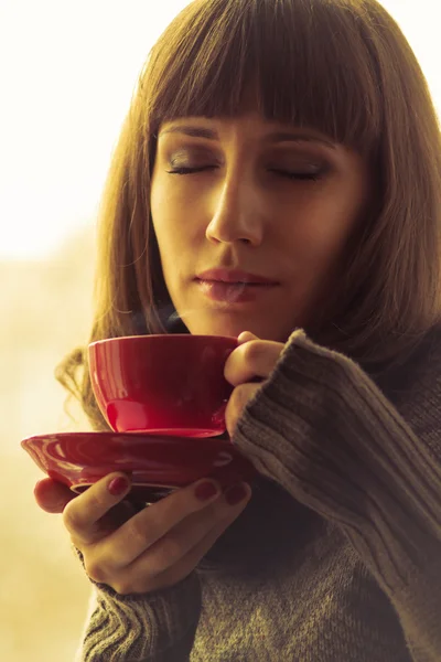 年轻漂亮的女人喝咖啡或茶与蒸汽。温暖的颜色色调 — 图库照片