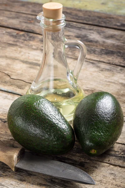 Two avocado with Knife and Bottle of Oil on Wood Background — Stock Photo, Image
