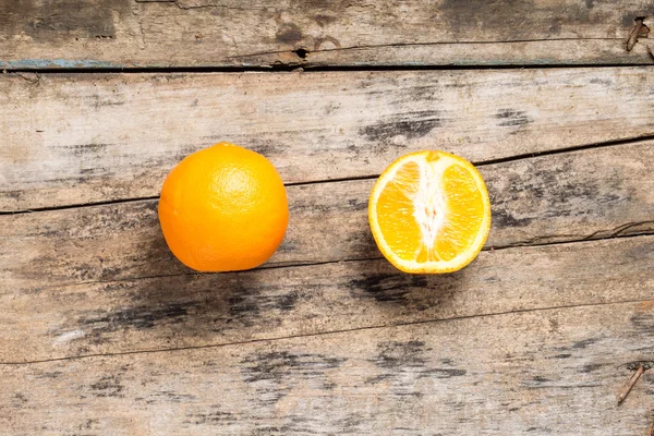 Hela och skär i halv apelsin liggande på texturerat vittrade trä — Stockfoto