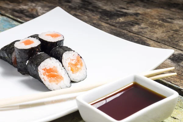 Makisushi σε λευκό πιάτο. θαλασσινά, παραδοσιακά Μάκη σούσι κυλίνδρους με chopsticks — Φωτογραφία Αρχείου