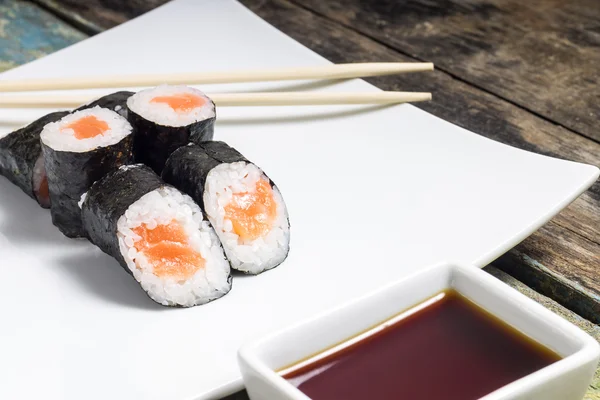 Makisushi σε λευκό πιάτο. θαλασσινά, παραδοσιακά Μάκη σούσι κυλίνδρους με chopsticks — Φωτογραφία Αρχείου