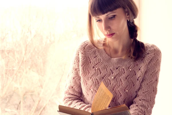 Genç kadın pencerenin yanında kitap okuma. — Stok fotoğraf