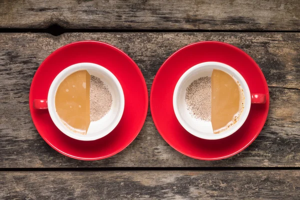 Half-full and half empty cups of coffee on wood background — Stock Photo, Image