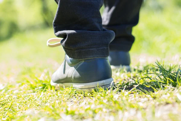 Spaceru na świeżym powietrzu. Zamknij się obraz chodzenia nogi w buty na trawie — Zdjęcie stockowe