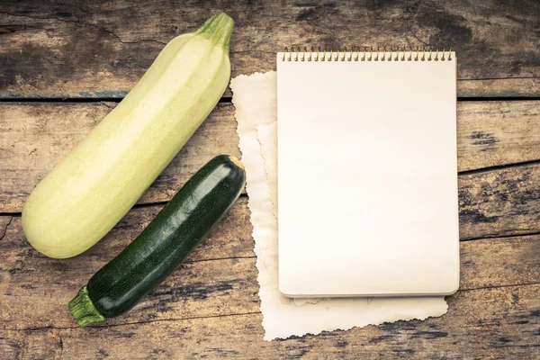 Série tonificada a cores quentes de legumes com livro de receitas em mesa de madeira . — Fotografia de Stock