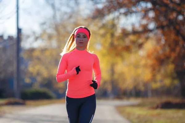 Young fitness woman running on the road in the cold morning in winter. — Stock Photo, Image