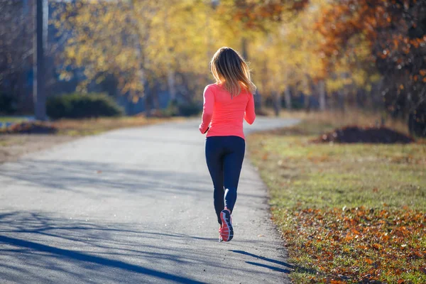 Young fitness woman running on the road in the cold morning in winter. — Stock Photo, Image