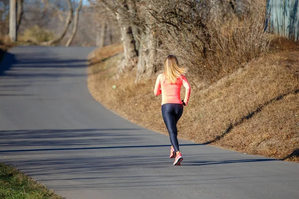 Young fitness woman running on the road in the cold morning in winter. — Stock Photo, Image