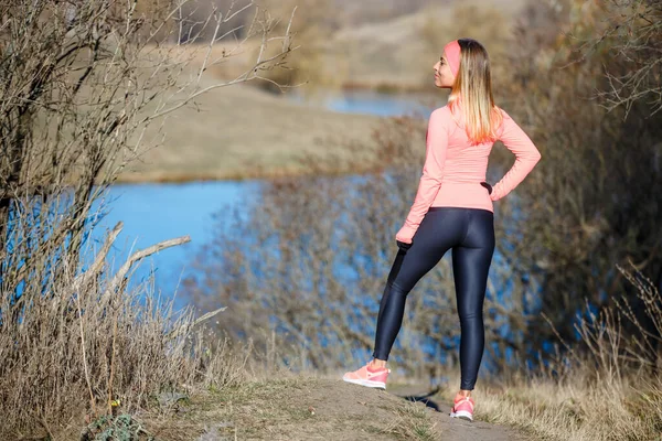 Jeune femme de fitness debout près de l'étang profitant de la nature après sa routine de jogging dans la matinée froide — Photo