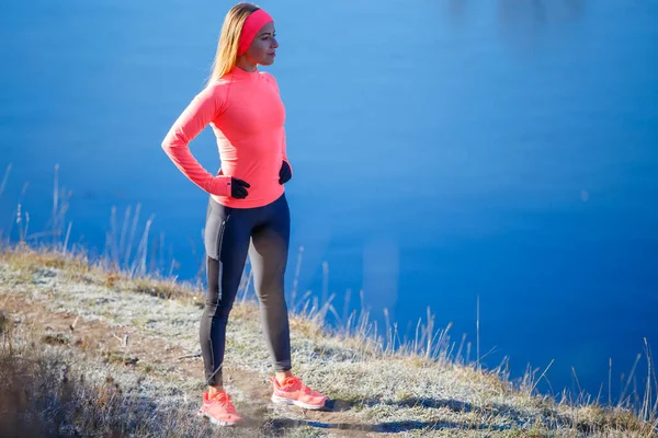 Young slim fitness woman resting near lake after her jogging in the frosty morning. — Stock Photo, Image