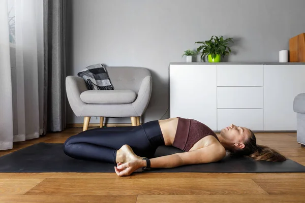 Giovane donna yogi che pratica yoga a casa. Apertura del cuore stretching fitness rilassante posa Foto Stock Royalty Free