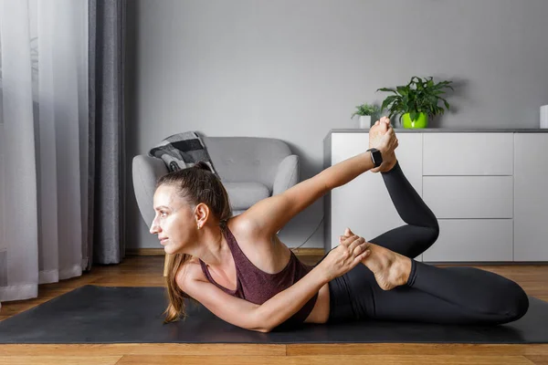 Giovane donna fitness che fa routine di yoga mattutina a casa. Fotografia Stock