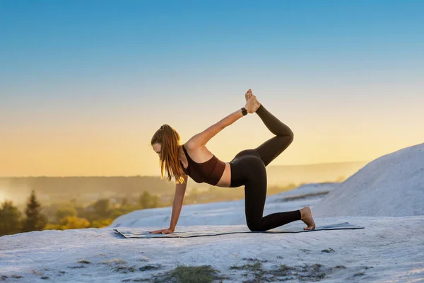 Giovane donna fitness che fa yoga all'aperto al tramonto Immagini Stock Royalty Free