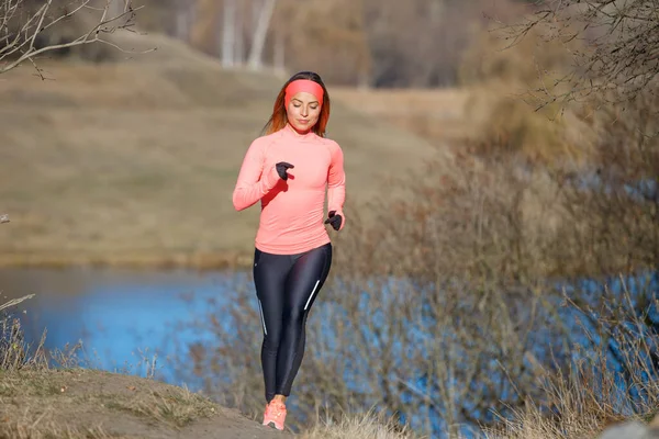 Young fitness woman running in the morning in cold sunny weather — Stock Photo, Image
