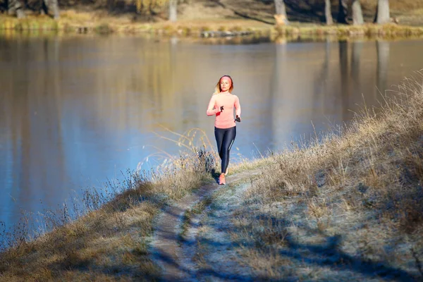 Fitness kızı buz gibi sabahta gölün yanında parkta koşuyor.. — Stok fotoğraf