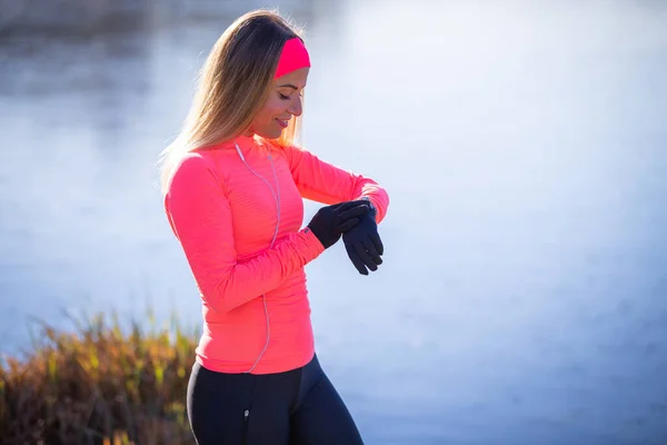 Young sporty woman checking her fitness tracker watch during morning running — Stock Photo, Image