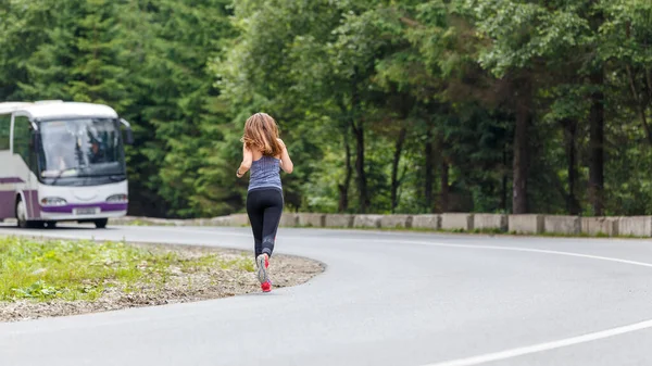 Runner woman running on the mountain road through the forest. — Stock Photo, Image