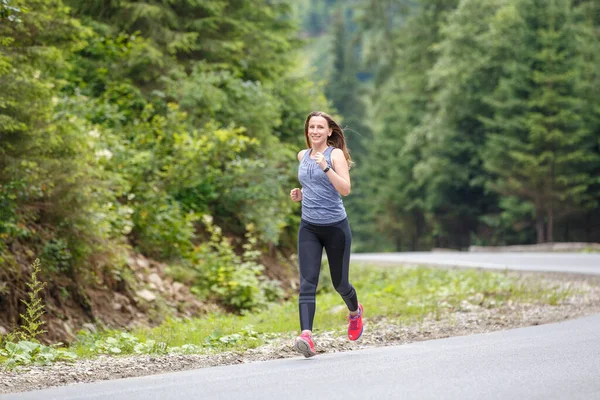 Donna corridore che corre sulla strada di montagna attraverso la foresta. — Foto Stock