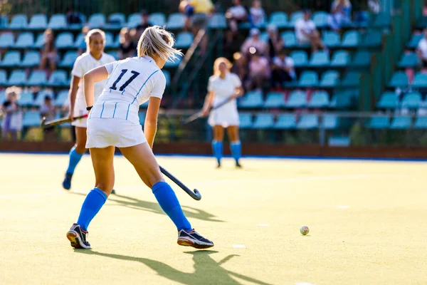 Young female field hockey player with the ball on the pitch — Stock Photo, Image