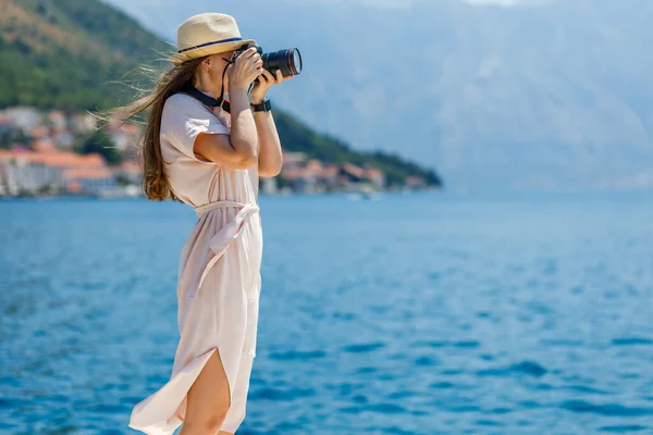 Joven dama de viaje en vestido toma fotos con la cámara profesional en el día soleado — Foto de Stock