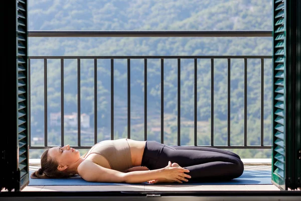 Young sporty women doing stretching lying on the mat at the balcony — Stock Photo, Image