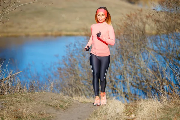 Young fitness woman running in the morning in cold sunny weather — Stock Photo, Image