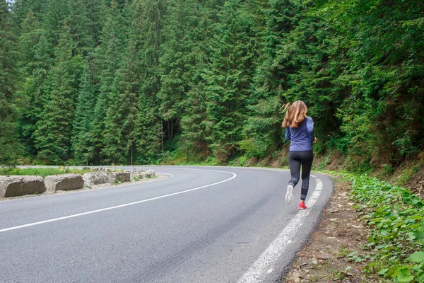 Femme coureuse courant sur la route de montagne à travers la forêt. — Photo