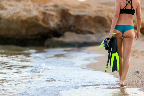 Ung attraktiv flicka med flippers vadar genom vattnet på stranden — Stockfoto