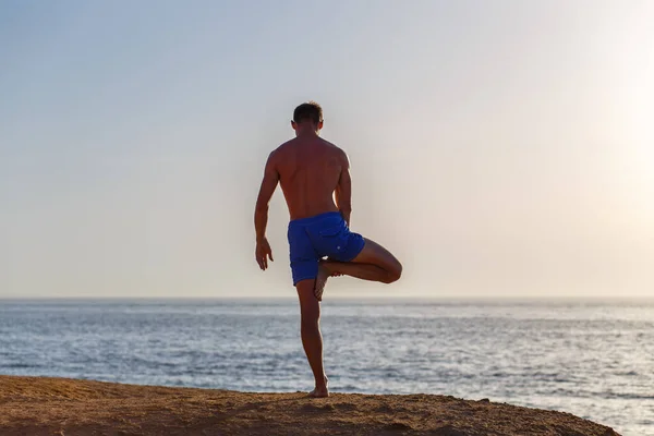 Joven practicando yoga en la playa por la mañana — Foto de Stock