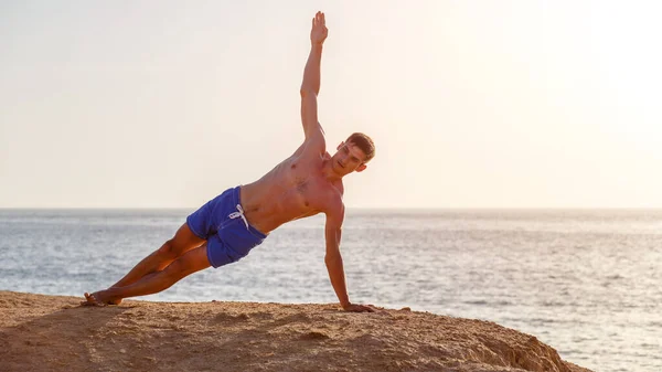 Junger Mann praktiziert morgens Yoga am Strand — Stockfoto