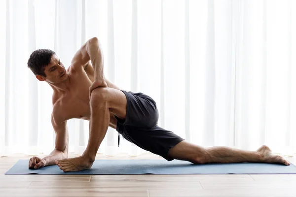 Giovane Uomo Yoga Facendo Gambe Stretching Durante Routine Mattutina Foto Stock
