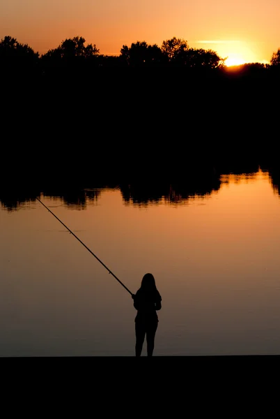 Kobieta wędkowanie na zachodzie słońca — Zdjęcie stockowe