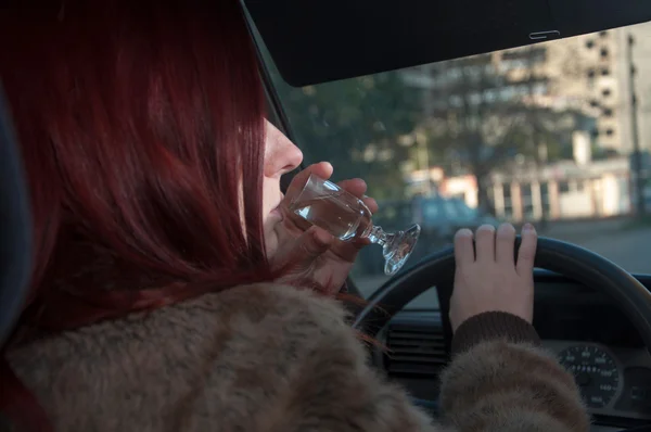 Dronken vrouw rijden auto met wodka in de hand — Stockfoto