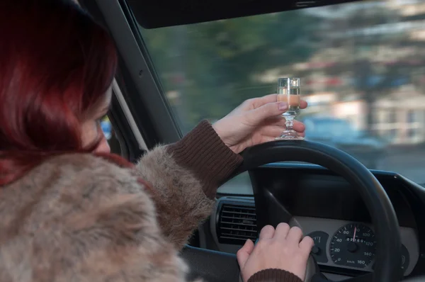 Drunk woman driving car with vodka in hand — Stock Photo, Image