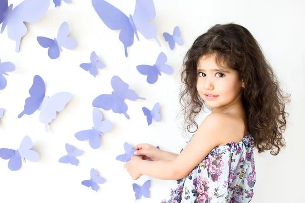A menina contra uma parede decorada com borboleta — Fotografia de Stock