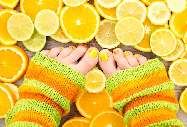 Female legs between citrus fruits — Stock Photo, Image