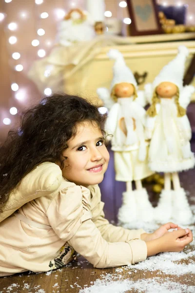 Uma menina encaracolada sorridente deitada no chão em traje de anjo — Fotografia de Stock