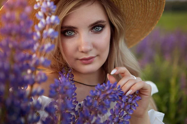 밀짚모자를 석양에 꽃피는 들판에 포즈를 취하고 아름다운 소녀의 — 스톡 사진