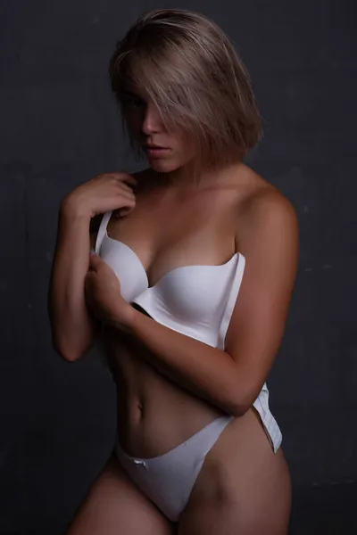 Eine hinreißende Blondine bedeckt ihre nackten Brüste mit ihren Händen und schaut bescheiden nach unten — Stockfoto