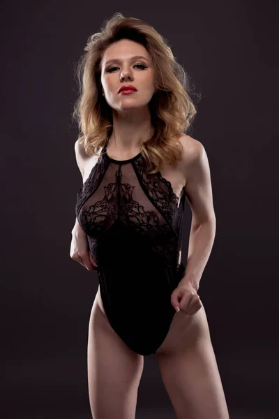 Сексуальная, красивая и привлекательная женщина с великолепным стройным телом, одетая в нижнее белье, позирующая в темной студии. — стоковое фото