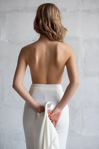 Estudio foto de una guapa rubia vestida de blanco Elegante traje de media vuelta contra una pared de ladrillo blanco —  Fotos de Stock