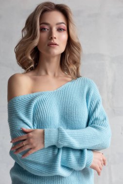 Beyaz arka planda mavi örgü süveter giyen seksi sarışın kız. Muhteşem bir yakın çekim modelinin moda fotoğrafı.