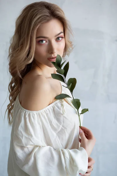 一个穿着白衬衫 手里拿着花的性感迷人女人的画像 灰色背景的演播室照片 — 图库照片